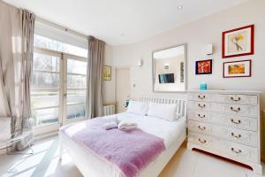 een slaapkamer met een bed, een dressoir en een raam bij 1 Bed Maisonette with Garden - 1 min to station Share Save in Londen