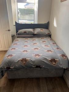 a bed in a bedroom with a bedspread on it at RB Contractor Stays - Ty Capel in Pwllheli