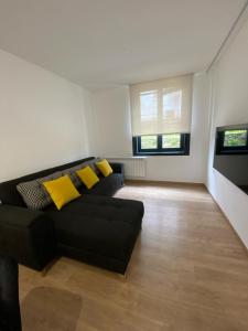 sala de estar con sofá negro y almohadas amarillas en Apartamentos Luisa, en Santiago de Compostela