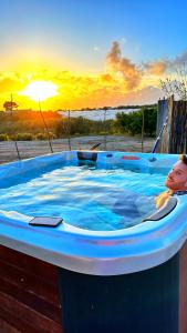 a child in a hot tub with the sunset in the background at Ciriga Sicily Glamping Resort in Santa Maria Del Focallo