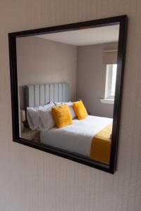 um espelho que reflecte uma cama com duas almofadas amarelas em Linwood House em Paisley