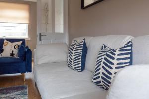 a white couch with blue and white pillows on it at Linwood House in Paisley