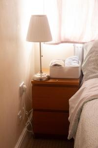a lamp on a night stand next to a bed at Spacious & bright 4-bedroom town-house with garden in Sydenham