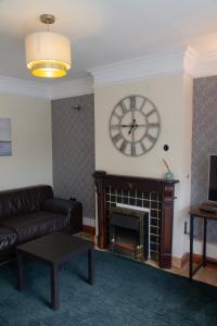 a living room with a clock above a fireplace at Spacious & bright 4-bedroom town-house with garden in Sydenham