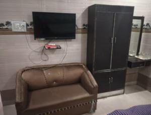 a brown chair and a tv and a cabinet at Goroomgo Riddhi Siddhi Haridwar Near Railway Station - Best Seller in Haridwār