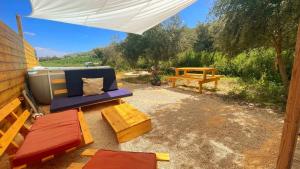 a patio with a blue couch and a picnic table at Dome in the Olive Grove כיפה גיאודזית ענקית ומודרנית בין עצי הזית in Yavneʼel