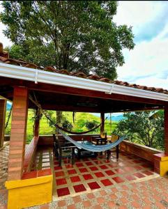 - une terrasse couverte avec un hamac, une table et un banc dans l'établissement Finca rincón del paraíso, à Los Andes