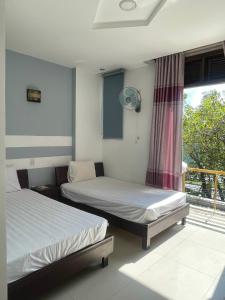 two beds sitting in a room with a window at CÁT TƯỜNG MOTEL in Da Nang