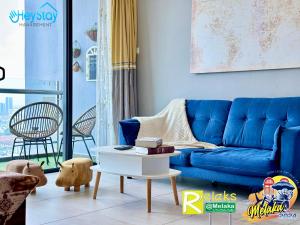 a living room with a blue couch and a table at Atlantis Residences Melaka by HeyStay Management(2) in Melaka