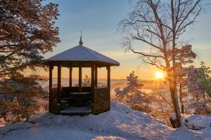 a gazebo in the snow with the sunset in the background at Hotel Jef a Krčma u Rytíře in Doubice