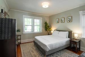 a bedroom with a white bed and two windows at Cincy East Side Cottage the best of Hyde Park in Cincinnati