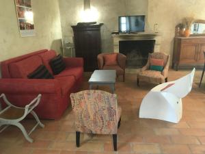 d'un salon avec un canapé rouge, des fauteuils et une cheminée. dans l'établissement Le Figuier, à Tulette