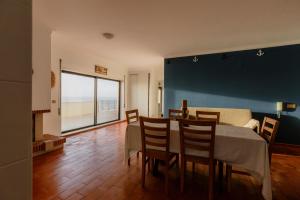 una sala da pranzo con tavolo, sedie e una grande finestra di Blue Apartments a Leiria