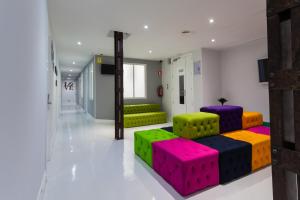 uma sala de estar com cadeiras coloridas e um sofá em Hostal Gran Via 44 em Madri