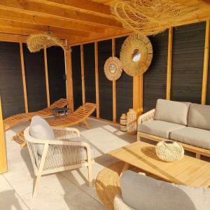 a patio with wicker chairs and a couch at Chalet, aux portes du Morvan in Voudenay-lʼEglise