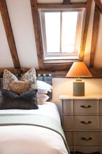 a bedroom with a bed with a lamp and a window at Mousehall Oast in Wadhurst