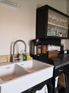 eine Küche mit einem weißen Waschbecken und einer schwarzen Theke in der Unterkunft Maison de famille piscine et vue in Sougères-en-Puisaye