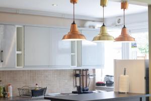 een keuken met witte kasten en koperen hanglampen bij Spacious & bright 4-bedroom town-house with garden in Sydenham