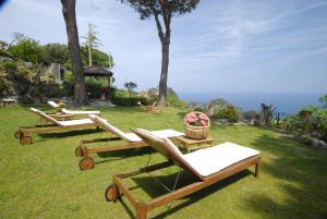 drie ligstoelen op het gras in een tuin bij Hotel Sant'Andrea in Marciana