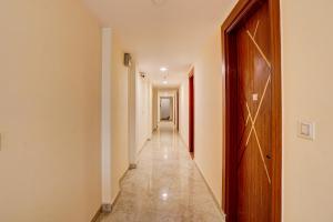 a hallway with a long corridor with white walls and a wooden door at Super OYO Flagship Red Diamond Hotel in Ghaziabad