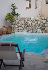 a swimming pool with a chair and a stone wall at Anassa Mountain House in Émbonas