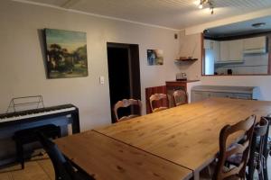 une salle à manger avec une table en bois et un piano dans l'établissement Maison familiale pour 10 personnes au centre à St Georges d'Oleron, à Saint-Georges-dʼOléron