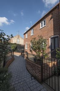 a brick building with a fence next to a sidewalk at Black Lion Court in Little Walsingham