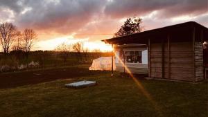 a house in a field with the sunset in the background at Ranczo Kowalskich in Karsin