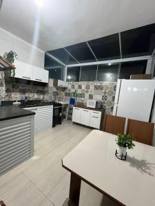 uma cozinha com armários brancos e uma mesa com uma planta em Maranduba Ville 2 em Ubatuba