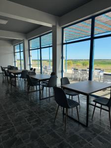 - un groupe de tables et de chaises dans une pièce avec fenêtres dans l'établissement Delta View, à Dunavăţu de Jos