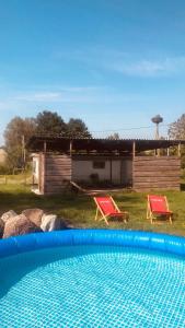 a swimming pool with two red chairs and a house at Ranczo Kowalskich in Karsin