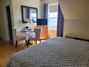 a bedroom with a bed and a desk and a mirror at Auberge Vue d'la Dune - Dune View Inn in Bouctouche