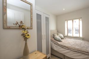 a bedroom with a bed with a mirror and a vase with flowers at Black Lion Court in Little Walsingham