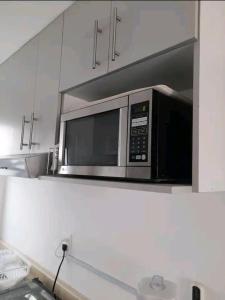 a microwave in a kitchen with white cabinets at Departamento Aeropuerto para 6 in Huejotzingo