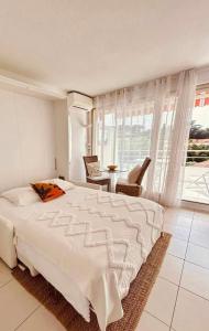 1 dormitorio con 1 cama blanca, mesa y sillas en Eden, en Saint-Tropez