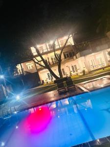 a swimming pool in front of a building at night at The Shade Brothers in Katunayake