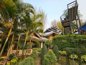 チェンマイにあるPhu Jaya Floresta Resort by ALPHATELのヤシの木が目の前にある家