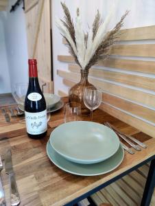 una mesa con un plato y una botella de vino en Le Tilleul et spa, en Bully