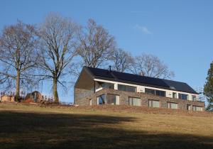 ein Haus mit Solardach auf einem Hügel in der Unterkunft Villa La Verdoyante in Lierneux