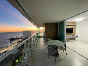 balcón con mesa, sillas y vistas al océano en Apartamento na Barra alto padrão com vista mar, en Salvador