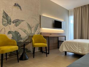 a bedroom with a bed and a desk with two yellow chairs at Casa Vacanze Fardella Centrale in Trapani