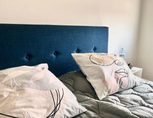 a bed with a blue headboard and pillows on it at Comme à la maison 10mn du Stade de France in Aubervilliers