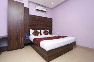 een slaapkamer met een bed met een houten hoofdeinde bij Collection O Hotel City Star in Raipur