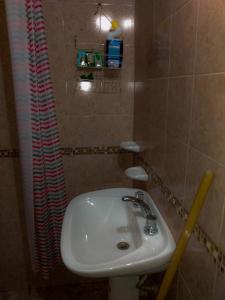 La salle de bains est pourvue d'un lavabo blanc et d'un rideau de douche. dans l'établissement LA TRANQUERA DPTOs, à Río Cuarto