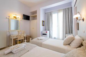 um quarto com 2 camas, uma secretária e uma janela em Kymata Hotel em Naxos Chora