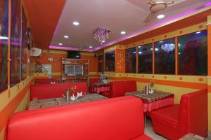 a restaurant with red chairs and tables in a room at OYO Raj Rajeswari in Āsansol