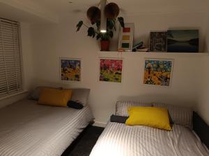 two beds in a room with paintings on the wall at Convenient Luton Rooms in Luton