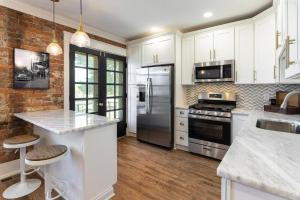una cocina con armarios blancos y electrodomésticos de acero inoxidable en The Gilded Cincy-View Condo, en Covington