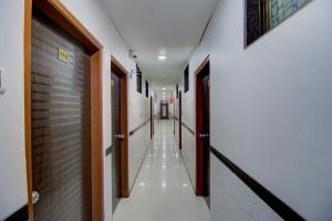 a long hallway with white walls and wooden doors at OYO Hotel Sion Residency in Mumbai