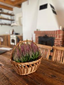 una cesta con flores púrpuras sentada en una mesa de madera en Domek nad Śniardwami, en Głodowo